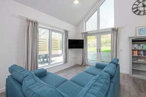 Ein großzügiger Wohnraum mit einer großen Couch, einem Flachbildfernseher und einem Bücherregal.