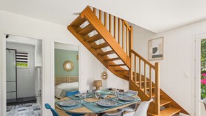 Un espace repas avec un escalier en bois, un lit doté d’une tête de lit et une vue sur l’extérieur.
