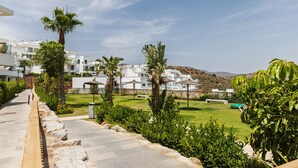 A pathway leading to a well-maintained lawn with palm trees and a view of white buildings. - Casa Banderas Sea & Valley Views by Alfresco Stays (Mijas)
