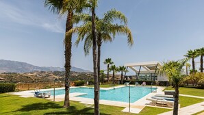 A pool area with a view of mountains, palm trees, and a modern building. - Casa Banderas Sea & Valley Views by Alfresco Stays (Mijas)
