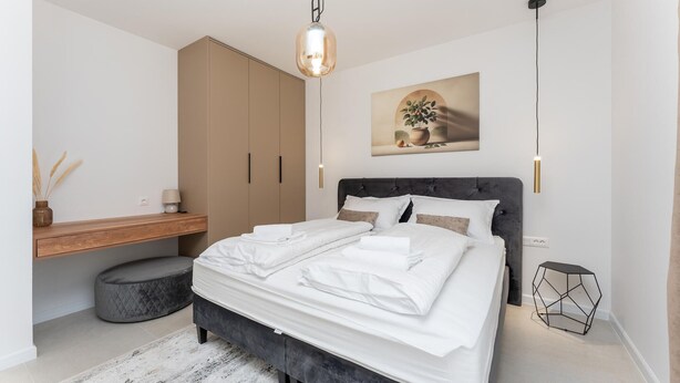 Un dormitorio moderno con cama, mesita de noche, armario y una planta en la pared.