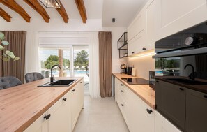 A modern kitchen with wooden countertops, a built-in oven, and a view of a pool. - Stunning home in Pridraga (Pridraga)
