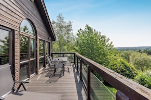 A wooden deck with outdoor furniture, large windows, and a view of a green landscape. - Host & Stay | 12 Belton Woods (Belton)