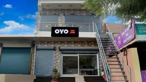 A hotel with a signboard reading 'OYO Hotel Aangan,' a staircase leading to the entrance, and a closed shutter on the left. - Hotel kartikey (Phulpur)