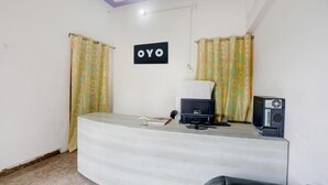 A reception desk with a sign that reads 'OYO,' a small flag, a computer, and a speaker. - Hotel kartikey (Phulpur)