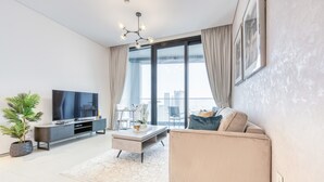 Ein modernes Wohnzimmer mit Flachbildfernseher, Sofa, Couchtisch und einem Topf mit Pflanze.