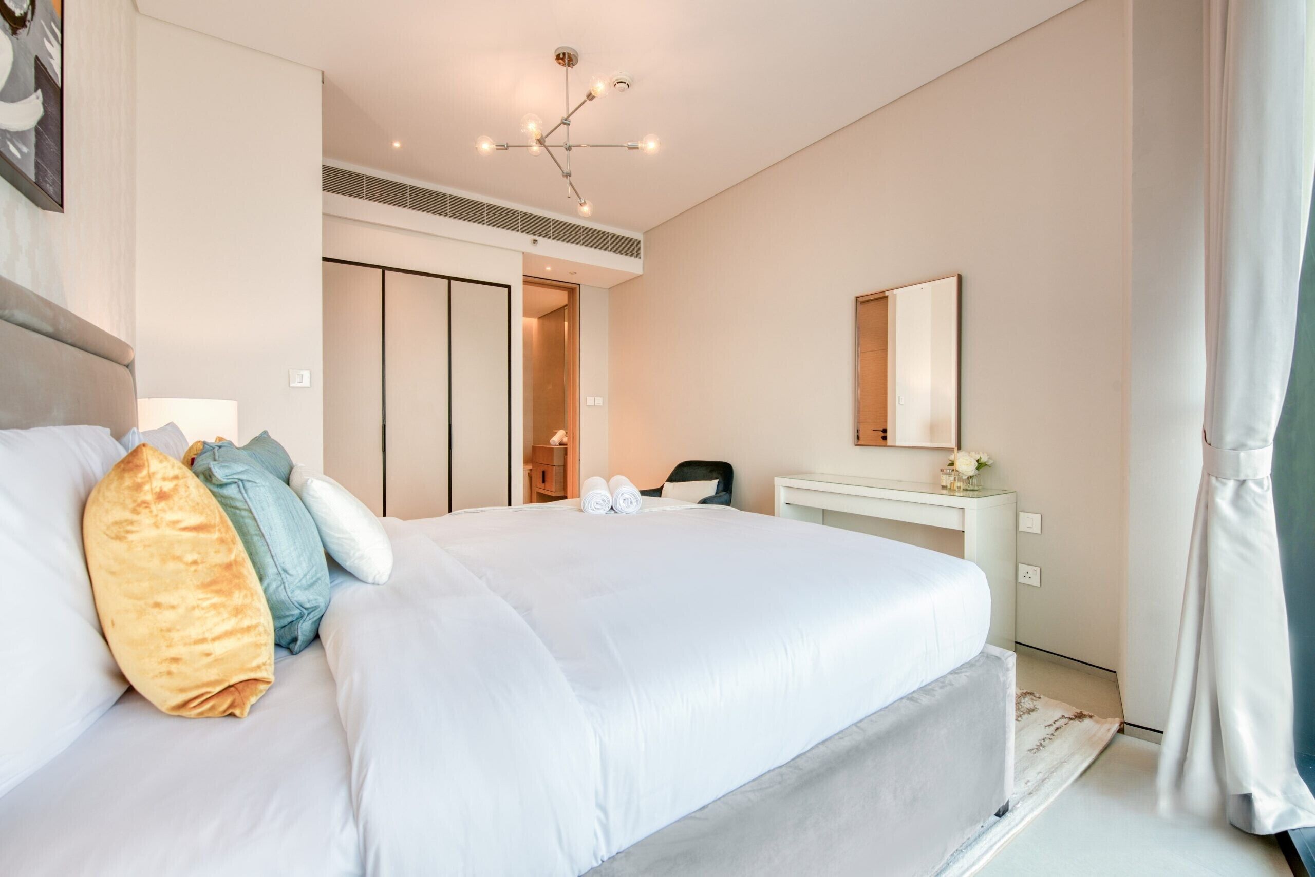 Une chambre d’hôtel moderne équipée d’un grand lit, d’un bureau, d’un miroir et d’une armoire.