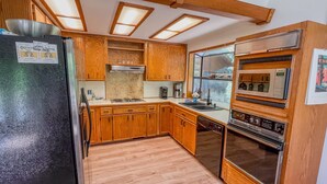 A kitchen with wooden cabinets, a refrigerator, a microwave, and a stove. - Wilderness Edge | Hot Tub, Wifi, Fireplace (Packwood)