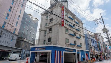 A hotel with a modern facade, multiple floors, and a prominent red sign.