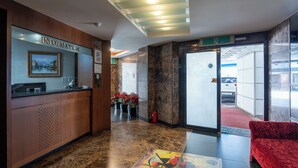 A reception area with a marble floor, a reception desk, a red sofa, and a glass door leading outside. - Yeongdeungpo Hotel Jago (Seoul)
