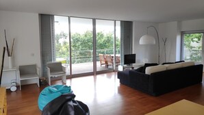 A modern living room with a sofa, a coffee table, a TV, and a balcony with outdoor furniture. - House with a private pool, Caminha (Viana do Castelo)