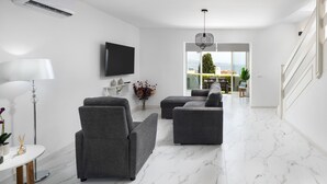 A modern living room with grey sofas, a flat-screen TV, a floor lamp, and a view of the outdoors. - AS MDS 172 in Mijas Costa (Mijas)