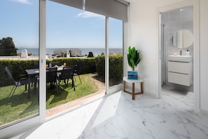 Ein modernes Zimmer mit einer großen Schiebeglas-Tür, die auf einen Balkon mit Meerblick führt.