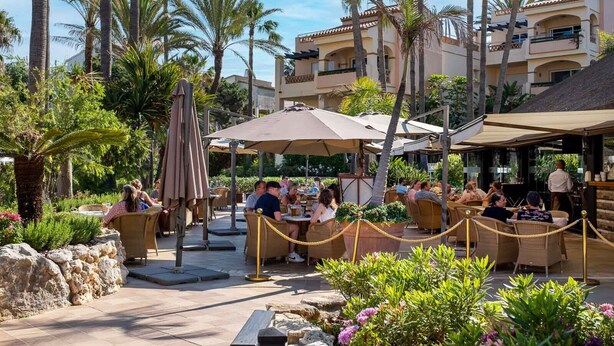 An outdoor dining area with tables and chairs, surrounded by palm trees and plants. - AS MDS 172 in Mijas Costa (Mijas)