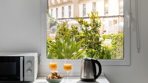 A kitchen with a microwave, a bowl of pastries, two glasses of orange juice, and a coffee maker by a window with a view of buildings and greenery. - AS MDS 172 in Mijas Costa (Mijas)