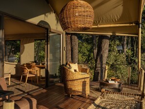 A wooden deck with wicker furniture, a table, and a hanging light fixture. - Thitaka River Lodge by NEWMARK - All Inclusive (Kongola)