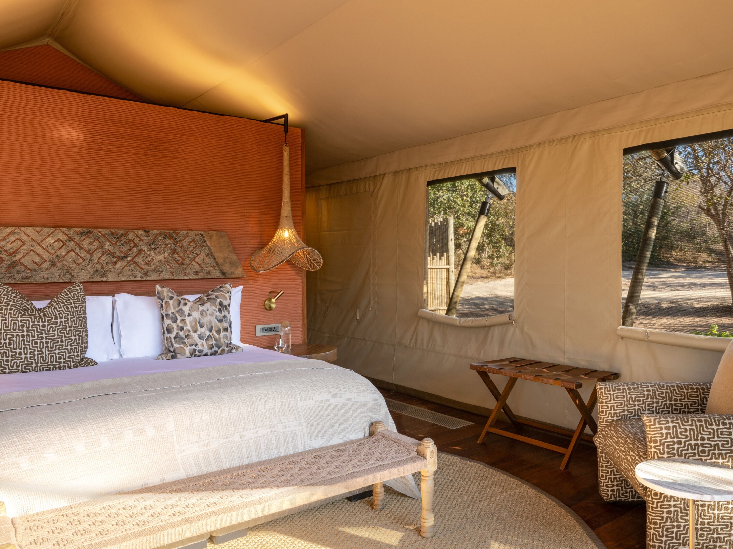 A bedroom with a large bed, a small table, and a view of the outdoors.