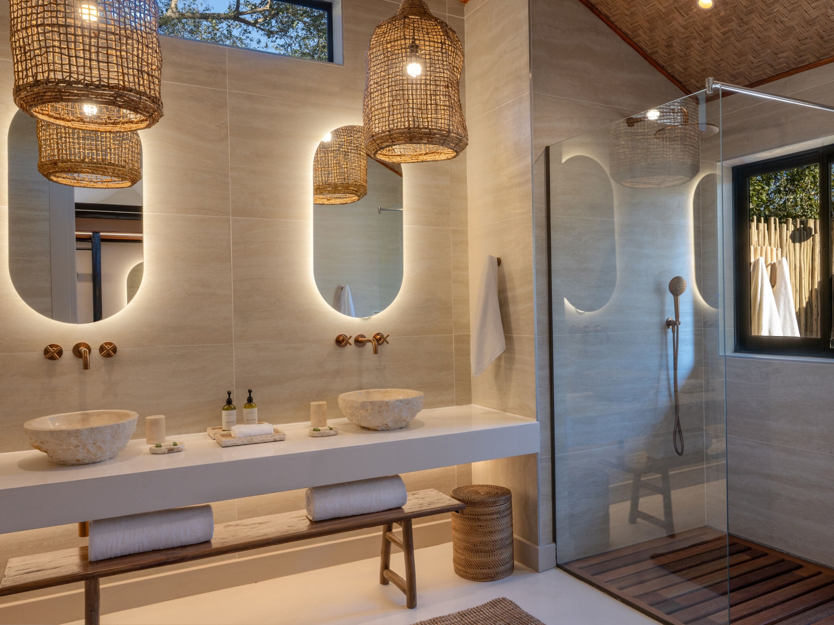 A modern bathroom with a large mirror, two sinks, and a glass shower enclosure.
