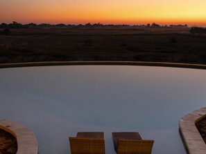 An outdoor seating area with two wicker chairs and a curved stone edge. - Thitaka River Lodge by NEWMARK - All Inclusive (Kongola)