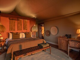 Un dormitorio con una cama grande, un banco de madera, un escritorio y una lámpara colgante.