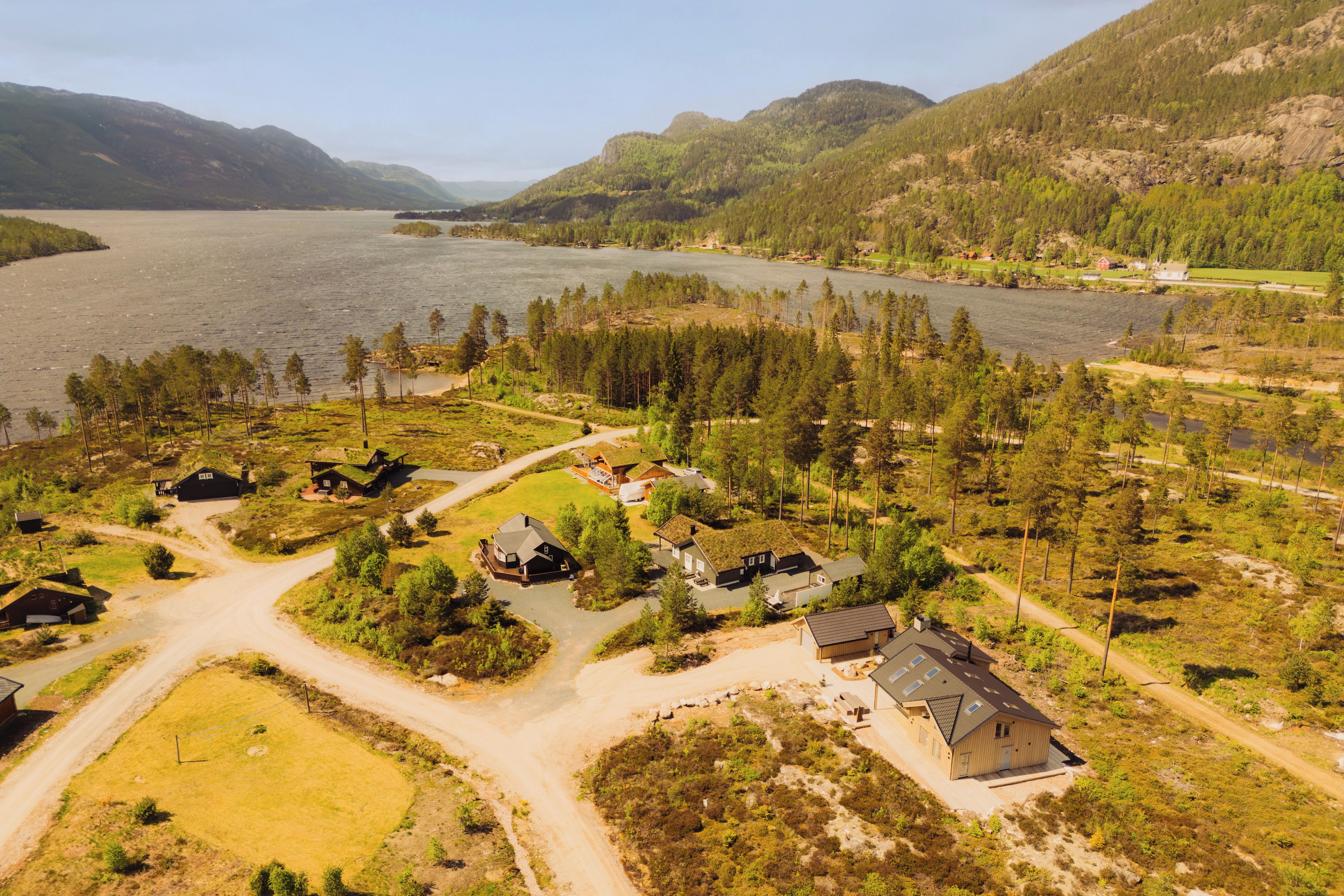 Una propiedad junto al lago con varias cabañas, una casa principal y un muelle para embarcaciones.