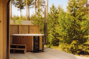 A wooden deck with a hot tub and a sauna.