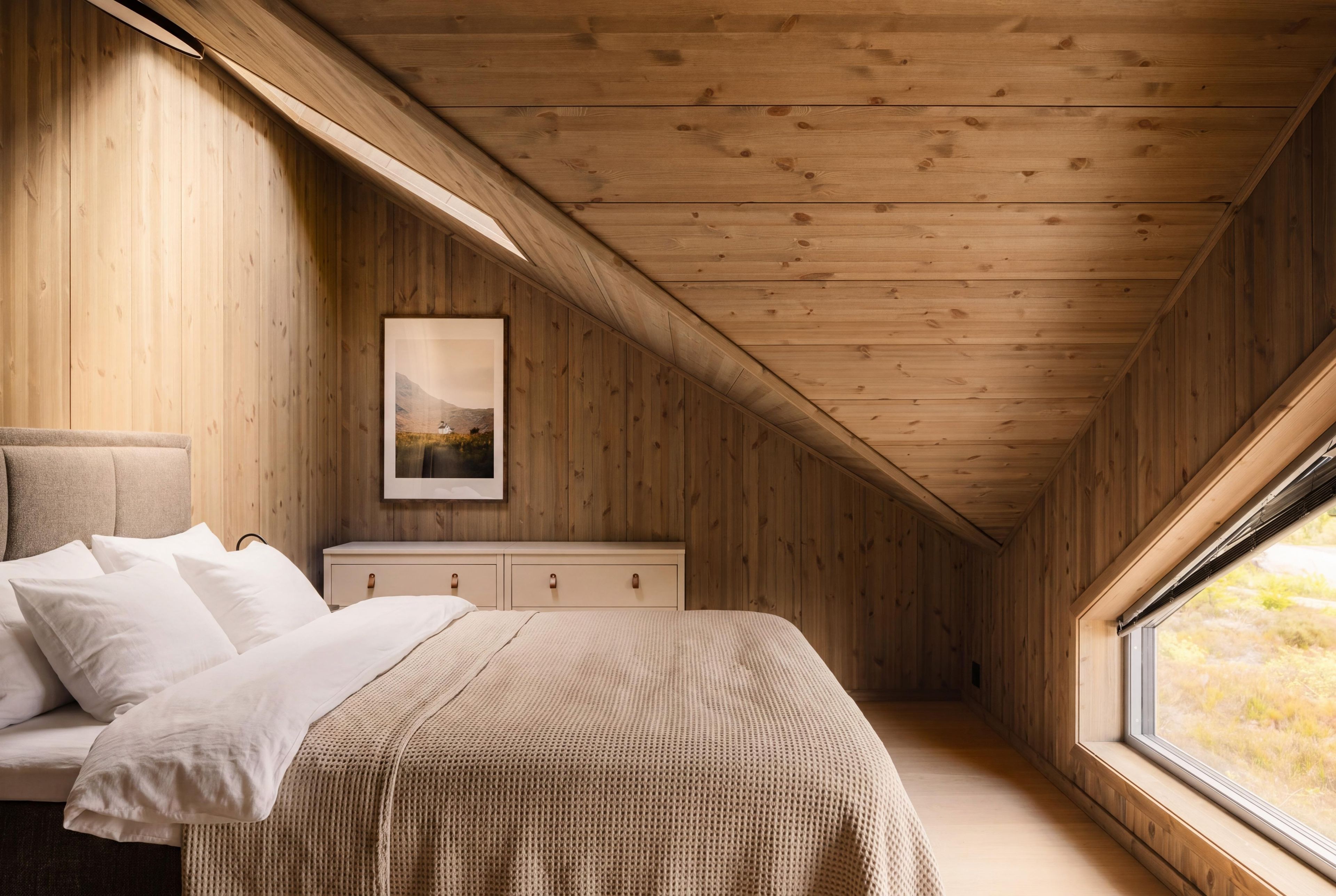 A bedroom with a bed, a nightstand, a dresser, and a window.