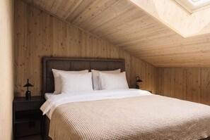 A bedroom with a wooden ceiling, a bed with white bedding, and two bedside lamps.