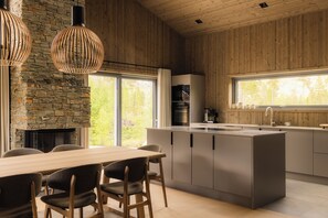 A modern kitchen with a stone wall, wooden ceiling, and large windows.