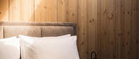 A bedroom with a wooden headboard, a bed with white linens, and a nightstand with a lamp.