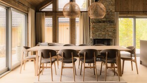 Un espace repas comprenant une grande table en bois, six chaises et deux luminaires suspendus.