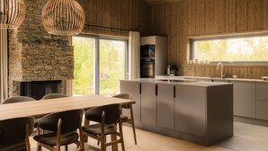 Une cuisine moderne avec un mur en pierre, un plafond en bois et de grandes fenêtres.