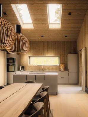 A modern kitchen with a central island, pendant lighting, and a large window.