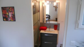A bathroom with a mirror, a sink, a red towel, and a small plant.