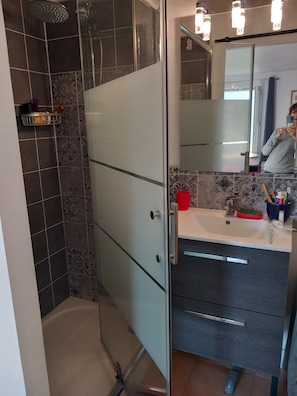 Ein Badezimmer mit Dusche, Waschbecken und Spiegel.