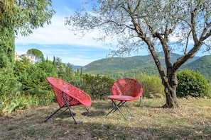 Two red chairs in a natural setting with a tree and a view of hills in the background. - Gîte de Maric: Among Olive Trees with Pool, Stunning Mountain Views (Aubres)