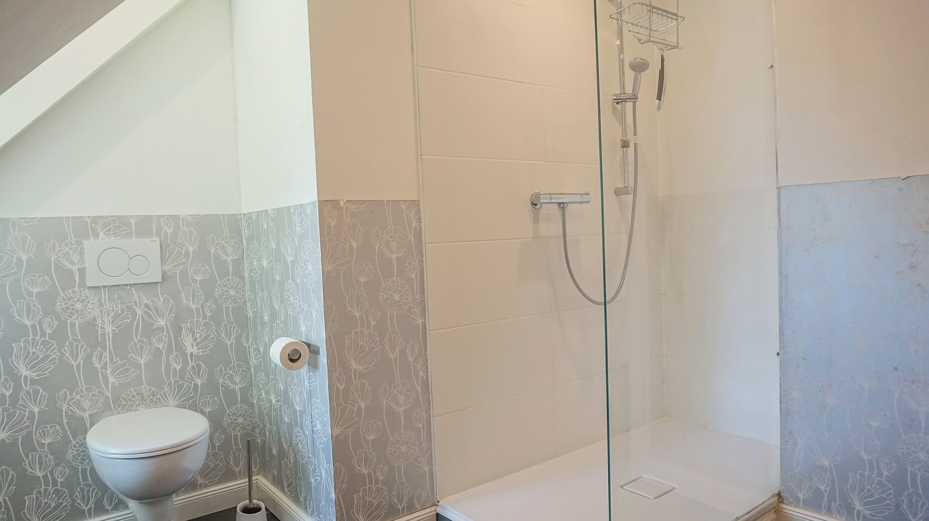 A bathroom with a toilet, shower, and a towel rack.