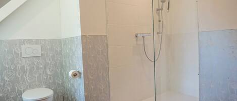 A bathroom with a toilet, shower, and a towel rack.