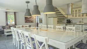 Una cocina moderna con armarios blancos, una campana de acero inoxidable y una isla integrada con asientos.