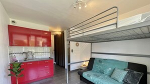 Ein kompakter Wohnbereich mit Küchenzeile, Etagenbett und Schlafsofa.