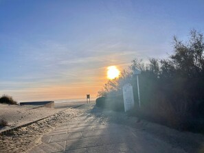 Ein Strandweg mit einem Wegweiser und Blick auf das Meer.