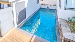 A rectangular swimming pool with clear blue water, surrounded by a wooden deck and stone walls. - House with AC and WiFi - 2 guests, near St-Pierre (Saint-Pierre)