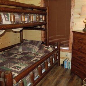 Ein Etagenbett mit Decke, einem Holz-Kopfteil und einem Fenster mit Jalousien.