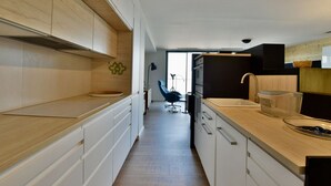 A modern kitchen with wooden cabinets, a sink, and a countertop. - Modern duplex, panoramic view - 6 guests (Évian-les-Bains)