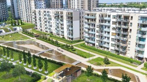 Un immeuble résidentiel de grande hauteur doté de nombreux balcons, d’une cour intérieure agrémentée d’éléments aquatiques et entouré de verdure.
