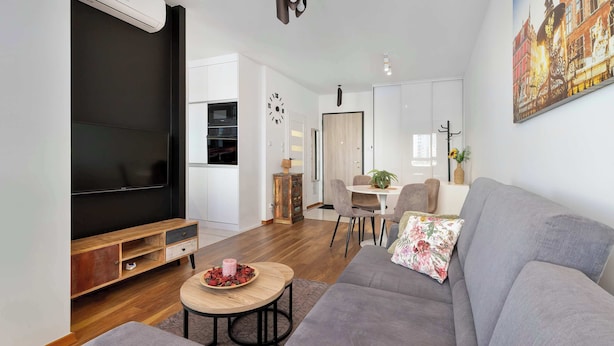 Un salon moderne avec un canapé gris, une table basse en bois et un téléviseur à écran plat.