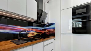 Une cuisine moderne avec des meubles blancs, un plan de travail en bois et un évier noir.