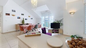 Ein modernes Wohnzimmer mit Essbereich, Fernseher und großem Fenster.