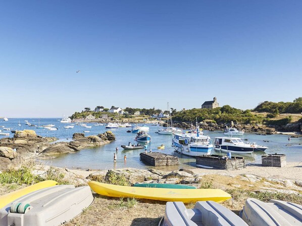 Un puerto costero con barcos, una costa rocosa y un edificio en una colina.