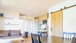 A compact living space with a sofa, dining table, chairs, a kitchen area with a microwave, and a sliding door. - Apartment, pets welcome, sea view - 4 guests (Le Lavandou)
